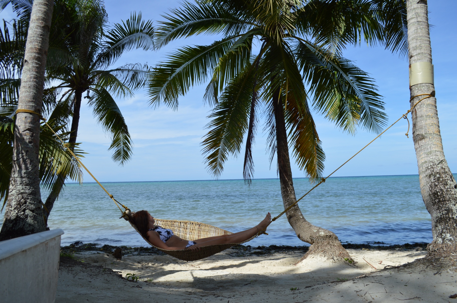 Hangmat tussen palmbomen op een wit zandstrand met turquoise zee in de Filipijnen